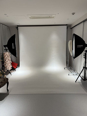 写真スタジオでピンクの花柄の振袖と白いファーのショールを身につけ、微笑む女性。和装のハンドバッグを持っている。