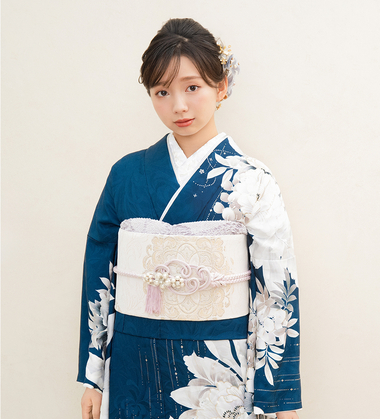 濃い紺色に大きな白い牡丹の花が描かれた振袖を着て、正面を向いて上品に微笑む女性。白地の帯と豪華なパールの帯飾りが特徴。
