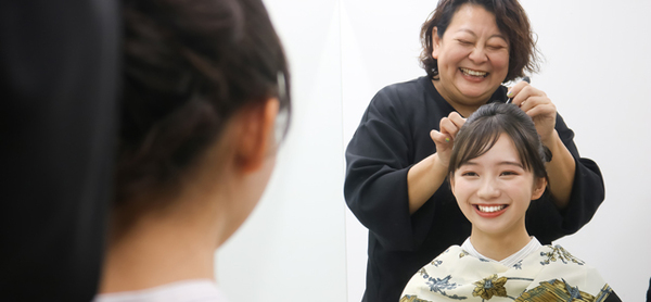 鏡越しに笑顔で会話しながら、専門スタッフにヘアセットをしてもらう女性